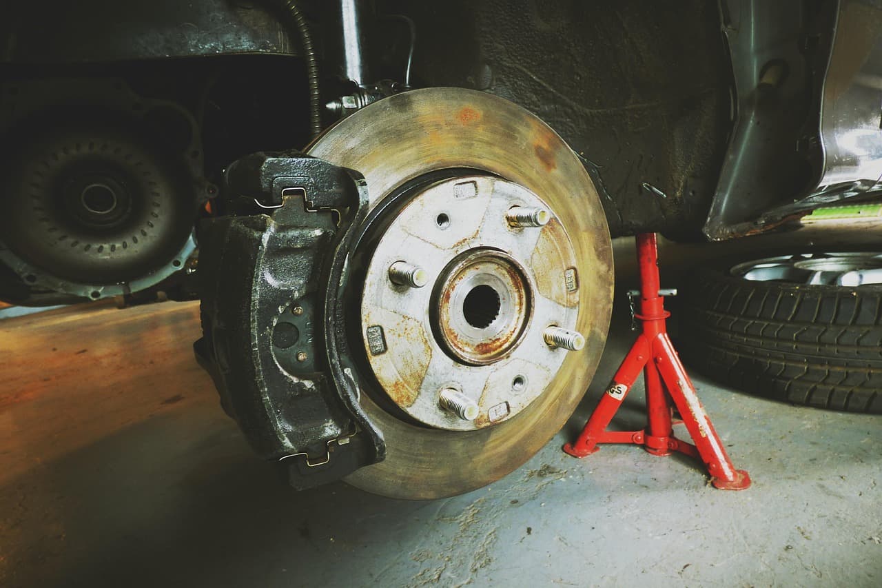 A brake disc on the car, axle stand beside it