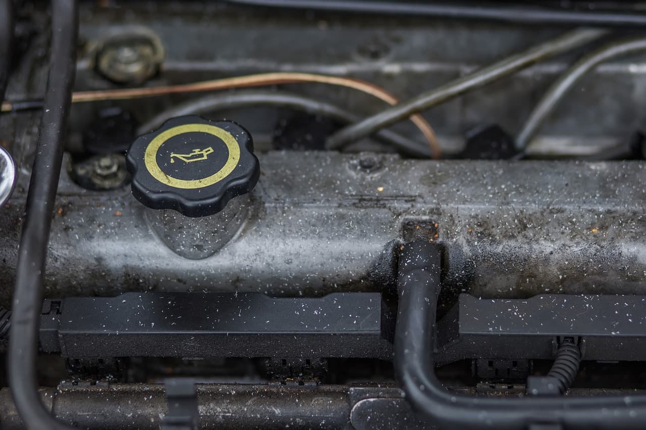 A grimy rocker cover and oil cap before a clean