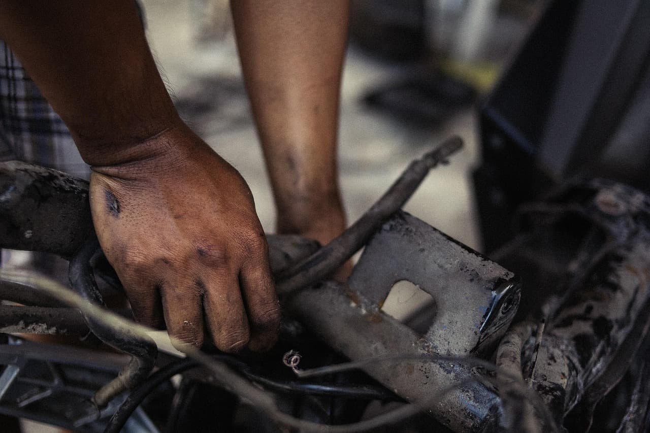 Oil-stained hands working a part loose