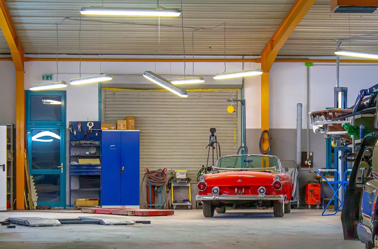A bright workshop with a car on the floor