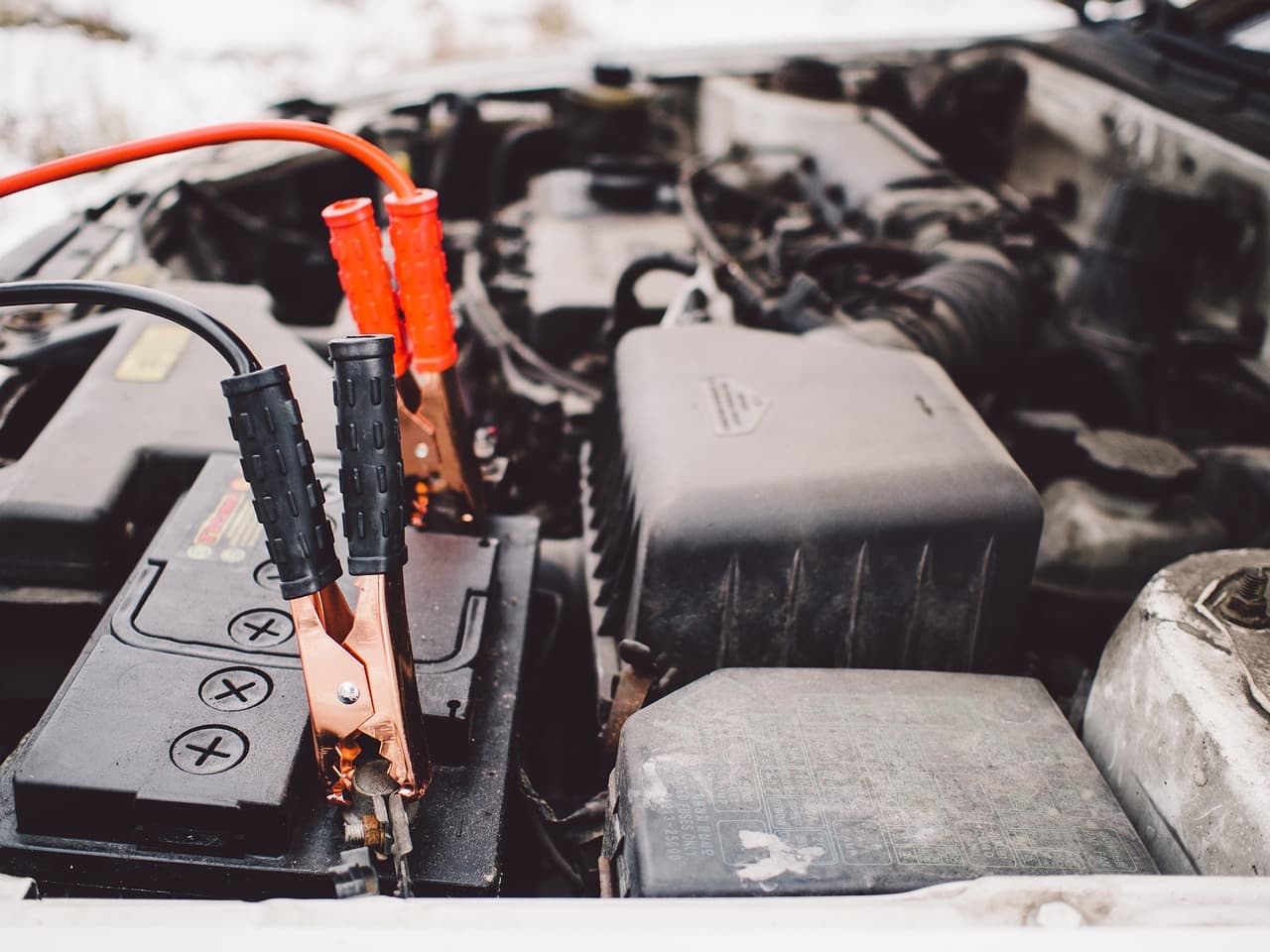 An engine bay with the battery and jump leads